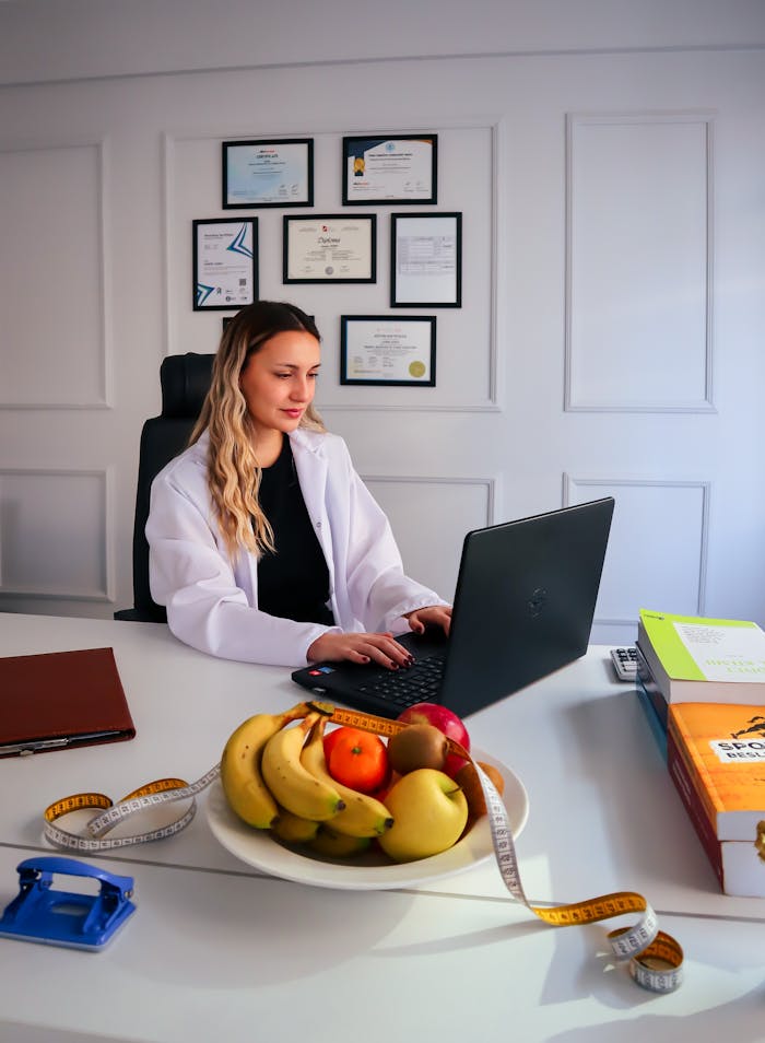 Dietitian at desk with fruits and laptop, representing healthy lifestyle and nutrition consultancy.