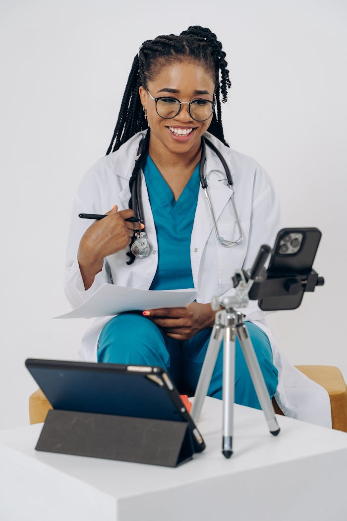 Smiling healthcare professional in scrubs using technology for an online consultation.