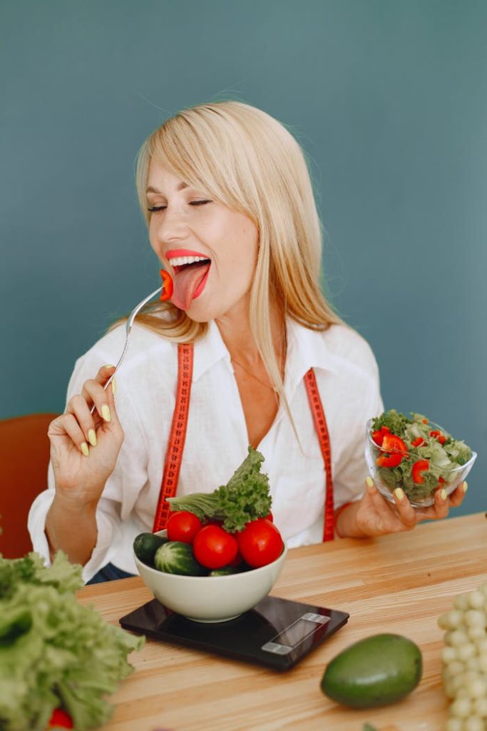Smiling woman savoring a fresh salad with tomatoes and greens, promoting healthy eating.